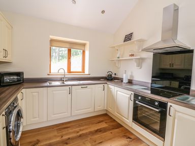 A kitchen with cream cabinets wooden countertops a window a stove oven and shelves at Pentre Fach in Llandrindod Wells