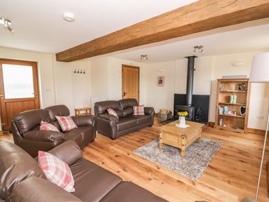 A living room with leather sofas a wooden coffee table on a rug and a fireplace at Pentre Fawr in Llandrindod Wells