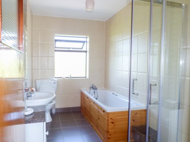 A bathroom with a sink toilet bathtub with wooden panel and a glass shower at Nephin View in Foxford County Mayo