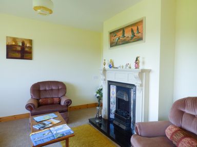 A living room with two armchairs a fireplace and a small wooden table with magazines at Nephin View in Foxford County Mayo
