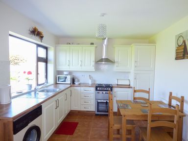 A kitchen with wooden table and chairs white cabinets and appliances at Nephin View in Foxford County Mayo