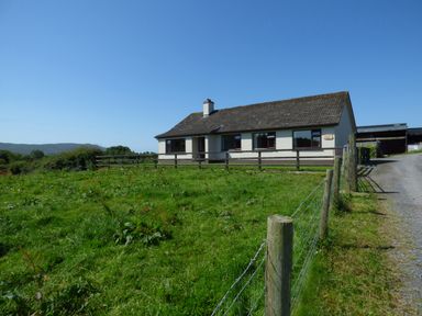 A single story house with a fenced grassy yard and a gravel driveway at Nephin View in Foxford County Mayo