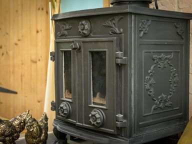 A close up of a black cast iron wood stove with decorative floral patterns at Rose Cottage in Edlingham