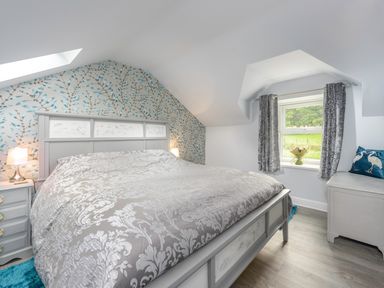 A bedroom with a large bed nightstand window with curtains and a chest at Rose Cottage in Edlingham