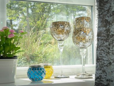 A windowsill with decorative glass candle holders and a potted plant at Rose Cottage in Edlingham