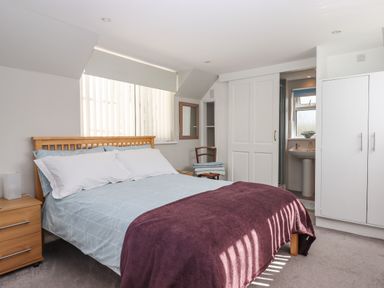 A bedroom with a double bed a bedside table a chair and an en suite bathroom at Wisteria Cottage in Exmouth