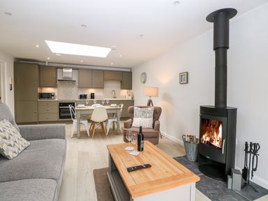 A living room and kitchen with a fireplace sofa armchair dining table and kitchen cabinets at Rabbit's Warren in Titchfield Common