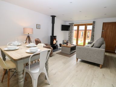A living room with dining table and chairs fireplace sofa and TV at Rabbits Warren in Titchfield Common