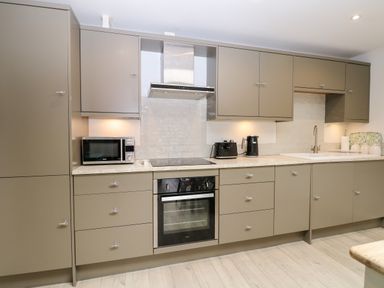 A kitchen with grey cabinets a microwave oven a stovetop a toaster a kettle a sink and a countertop at Rabbits Warren in Titchfield Common