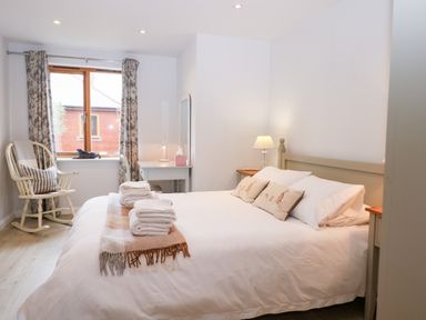 A bedroom with a bed towels rocking chair and desk at Rabbits Warren in Titchfield Common