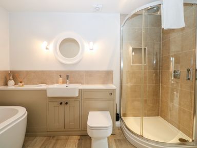 A bathroom with a bathtub a sink with cabinets a toilet and a glass shower at Rabbits Warren in Titchfield Common
