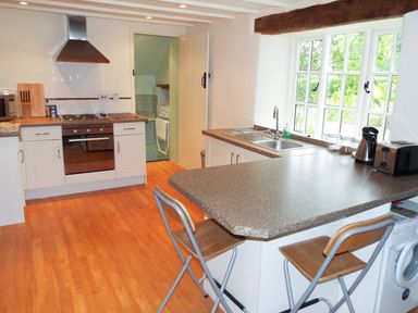 A kitchen with countertops stools stove oven sink and window at The Granary in Walford near Ross-on-Wye