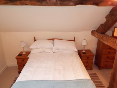 A bedroom with a double bed two bedside tables with lamps and wooden beams at The Granary in Walford near Ross-on-Wye