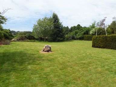 A garden with a grass lawn a tree stump trees a swing set and hedges at The Granary in Walford near Ross-on-Wye