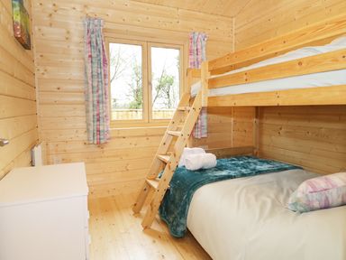 A bedroom with wooden bunk beds a dresser and a window with curtains at The Shippen in Merriott