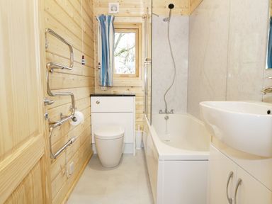 A bathroom with a bathtub shower combination toilet sink and towel rack at The Shippen in Merriott