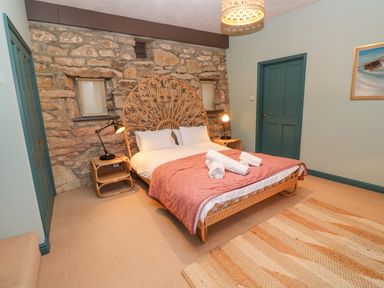 A bedroom with a bed and stone wall at Barn Cottage in Marazion