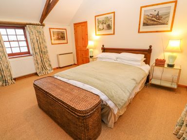 A bedroom with a double bed bedside tables lamps a wicker storage chest under window at Barn Cottage in Marazion