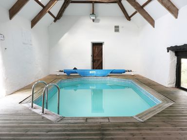 An indoor pool with wooden floor and beams on the ceiling at Carthorse Cottage in Teignmouth