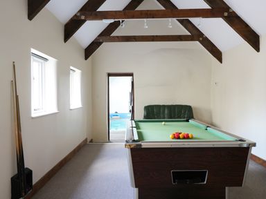 A room with a pool table near two windows and a green couch at Carthorse Cottage in Teignmouth