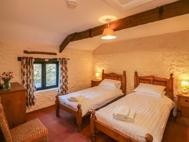 A bedroom with two single beds with white linens and wooden frames at Carthorse Cottage in Teignmouth
