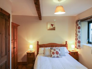 A bedroom with a wooden bed and nightstands with lamps at Carthorse Cottage in Teignmouth