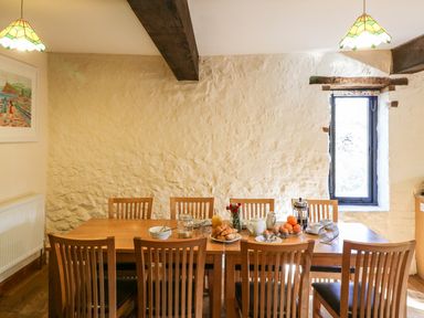 A dining room with a wooden table and chairs and breakfast items at Carthorse Cottage in Teignmouth