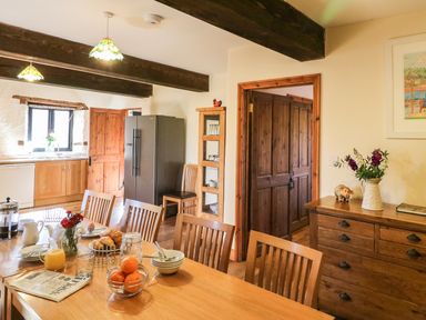 A kitchen dining room with wooden furniture and a table set with breakfast items at Carthorse Cottage in Teignmouth