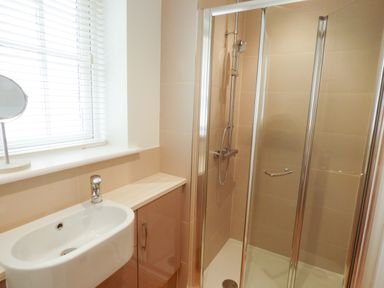 A bathroom with a shower enclosure sink with tap cabinet and window blinds at The Hideaway in Verwood