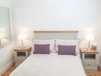 A bedroom with a bed with two pillows and two bedside tables with lamps at The Hideaway in Verwood