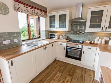 A kitchen with wooden countertops white cabinets a sink toaster microwave oven and utensils at Stoney-Brook Lodge in Bedlam near Ludlow