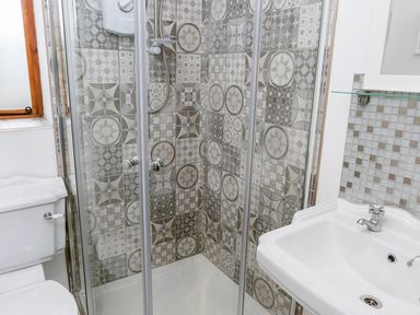 A bathroom with a shower enclosure with patterned tiles a white sink and a toilet at Stoney-Brook Lodge in Bedlam near Ludlow