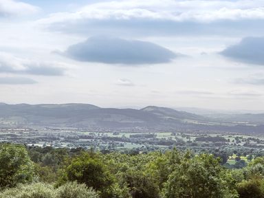 A landscape view of hills and green fields with trees under a cloudy sky at Stoney-Brook Lodge in Bedlam near Ludlow