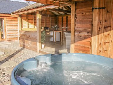 An outdoor hot tub next to a wooden gazebo with a small bar area at Stoney-Brook Lodge in Bedlam near Ludlow