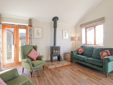 A living room with armchairs sofa a wood burning stove and wooden floor at Stoney-Brook Lodge in Bedlam near Ludlow