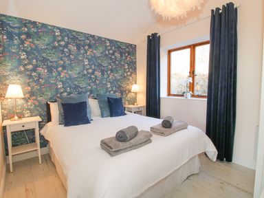 A bedroom with a double bed with pillows bedside tables with lamps and a window with curtains at Stoney-Brook Lodge Bedlam near Ludlow