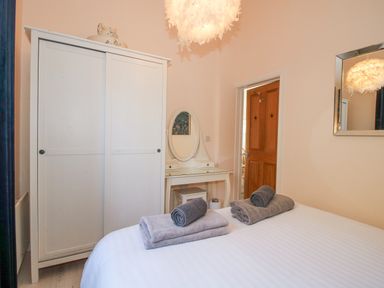 A bedroom with a white wardrobe a dressing table a mirror and towels on a bed at Stoney-Brook Lodge in Bedlam near Ludlow