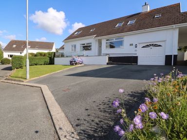 A house with a garage and flower bed at Bay View in Benllech