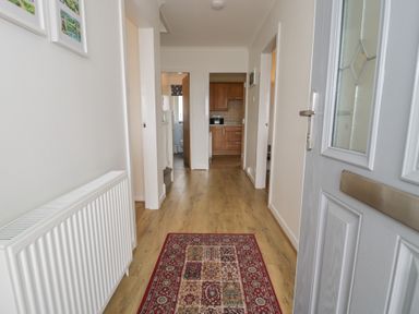 A hallway with a door and access to kitchen and bathroom at Bay View in Benllech