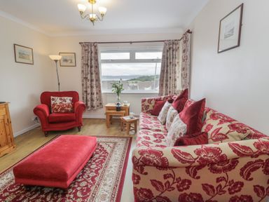A living room with a sofa and armchair at Bay View in Benllech