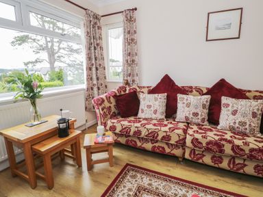 A living room with a floral sofa and coffee table at Bay View in Benllech