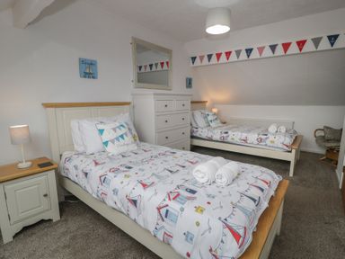 A bedroom with two beds and a dresser at Bay View in Benllech