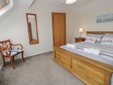 A bedroom with a bed and a chair at Bay View in Benllech
