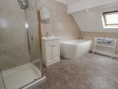 A bathroom with a shower and bathtub at Bay View in Benllech