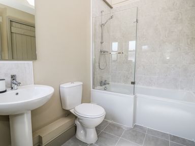 A bathroom with a sink, toilet, and bathtub with a shower at Providence Cottage in Easingwold