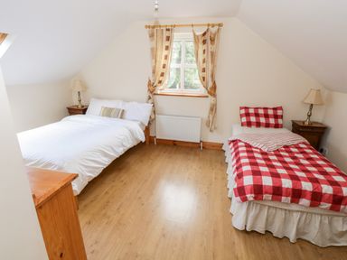 A bedroom with two beds a window and two bedside tables with lamps at Lough Mask Road Fishing Cottage Ballinrobe County Mayo