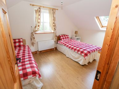 A bedroom with two single beds covered in red and white checkered bedding at Lough Mask Road Fishing Cottage in Ballinrobe County Mayo