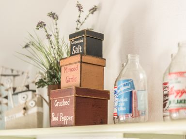Three stacked wooden spice containers labeled Grounded Salt Minced Garlic and Crushed Red Pepper with glass bottles and a plant in the background at The Snug in Rescorla near St Austell