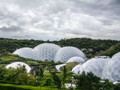 Several large geodesic domes surrounded by trees and greenery under a cloudy sky