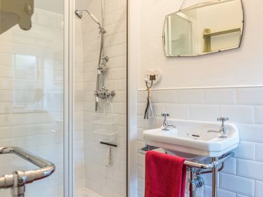A bathroom with a shower enclosure and a sink with a red towel at The Snug in Rescorla near St Austell